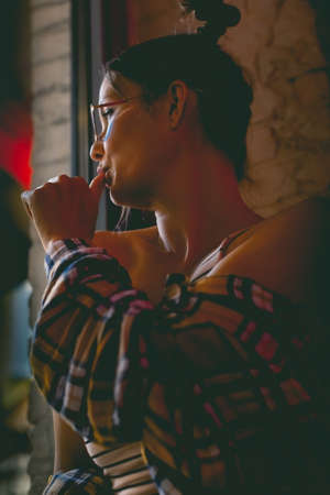 Portrait of an attractive and mysterious woman wearing blue glasses, shot in dark colors. Vertical photo.の写真素材