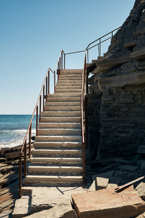 Stairs to the beach surrounded by rocks. Vertical photo.