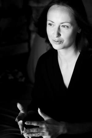 Black and white photo of an attractive smiling woman. A large portrait on a dark background. Vertical photo.の写真素材