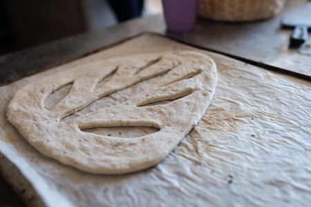 A baker shapes and cuts traditional French Fougasse bread. Front view.