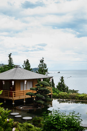 Japanese-style house by the sea. View of the sea, rocks and forest. Vertical photo.