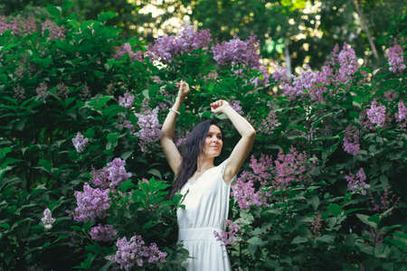 Portrait of an attractive woman surrounded by lilac bushes. Spring and summer, seasonal photos. Front view.の写真素材