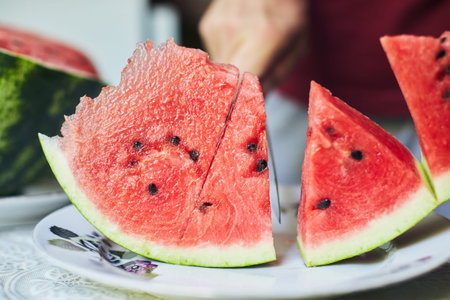 Juicy red watermelon is cut with a knife. The concept of summer and delicious vegetables. Front...
