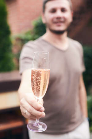 A friend raises a glass of champagne in your honor at a house party. Selective focus. Vertical photo.の写真素材