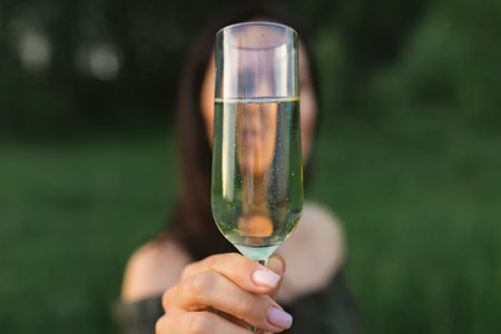 An attractive woman with a glass of champagne on a forest plot in the middle of nature. Front view.の写真素材