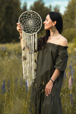 An attractive woman in a summer field with a dream catcher. Vertical photo.の写真素材