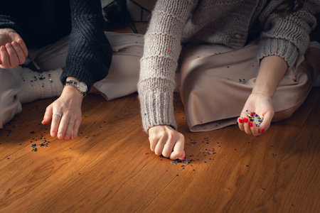 Two girls collect confetti stars from the floor for Christmas. Front view.の写真素材