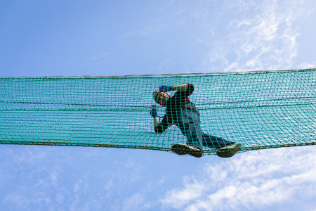 A man is resting in a rope amusement park. Front view.の写真素材