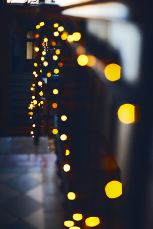 The staircase in the building at Christmas in a glowing garland goes up to the mirror. Blurred background. Vertical photo.の写真素材