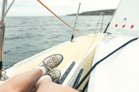 Legs of a woman in sneakers on a sports yacht at sea. Front view.の写真素材