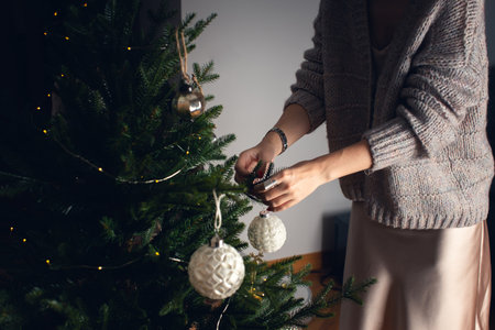 A girl decorates a Christmas tree for Christmas with balls. Front view.の写真素材