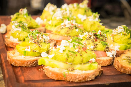 smashed avocado cook with fetta cheese and drill put on top of cucumber and bread are served on the...
