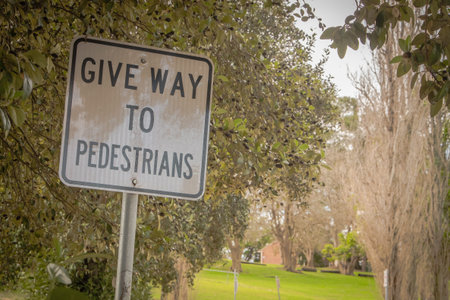 close up "give way to pedestrians" sign is showing on the left side to warn the driver to speed slowly and carefully the people who want to cross or use the street ( brown tone)の写真素材