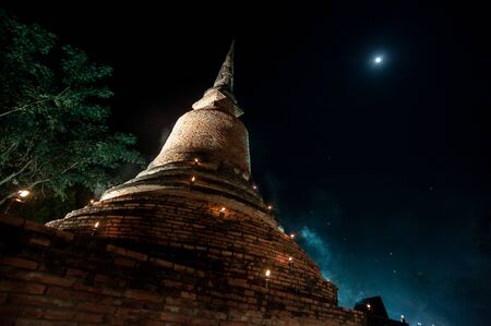 Temple at the Sukhothai Historical Park in the full moon night during the Loykratong festivalの写真素材