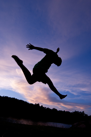 Silhouette happy jumping against beautiful in sunset. Freedom, enjoyment conceptの写真素材