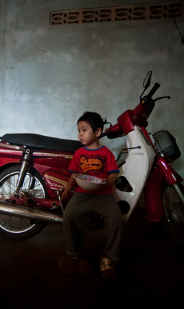 PAKSE, LAOS, August 14 : An unidentified Laos little boy sitting eating in the house of PAKSE, LAOS on August 14, 2010のeditorial素材