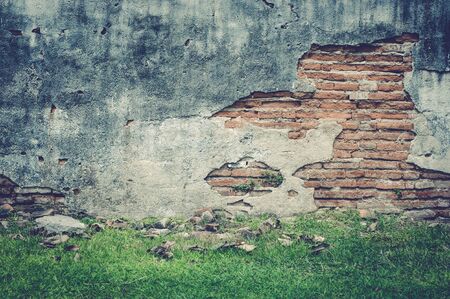 Red cracked brick wall with green grass floorの写真素材