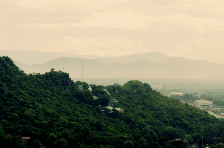 City and countryside scape with blue sky, clouds and green grass in the summer dayの写真素材