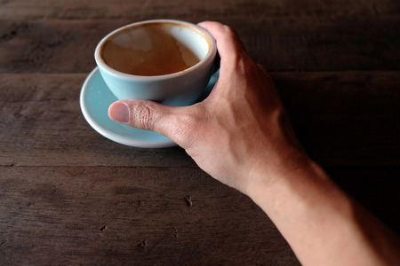 hands holding hot cup of coffee on rustic wooden table backgroundの写真素材