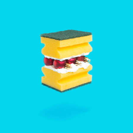 From a yellow dishwashing sponge and red Christmas decorations, made a hamburger. Blue background of a creative idea. Fast food.の写真素材