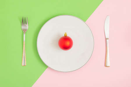 Meal utensils, neatly arranged on a colorful table. There is a red Christmas decoration in the plate. Abstract creative composition. New Year 2022の写真素材