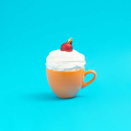 In the yellow coffee salt with whipped cream, a red Christmas decoration was placed. Minimal idea xmas. New Year 2022の写真素材