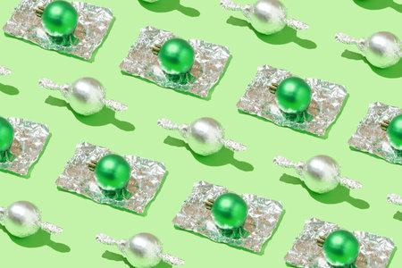 A pattern of candies wrapped in aluminum foil and one that is open. Christmas background. 2022