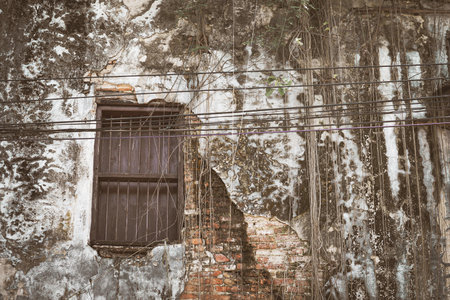 A wooden window with iron grilles mounted on an old brick wall tの写真素材