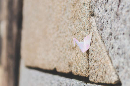 The glossy paper bird was tucked on the seam of a brick wall.の写真素材