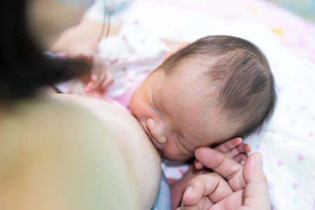 Close-up photo of an Asian baby feeding on her mother's breast. soft focus.の写真素材