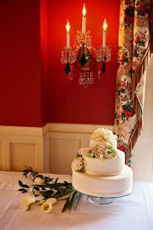 beautiful wedding cake covered with roses, bright red wall in the backgroundの写真素材