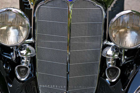 close up of a vintage black cars grill and headlampsの写真素材