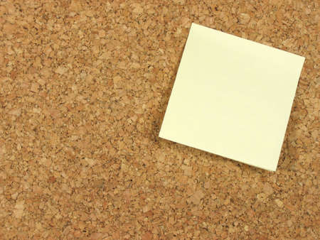 Blank yellow note paper stick on a corkboardの写真素材