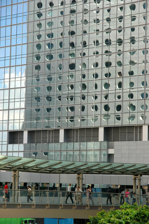 People walking on a bridge with background of a building reflection