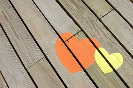 Background of orange and yellow hearts on wooden floorの写真素材