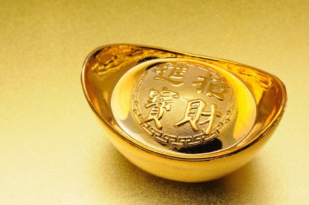Close up of chinese gold ingot over golden backgroundの写真素材