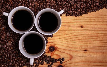 Black coffee on a wooden background surrounded by coffee beansの写真素材