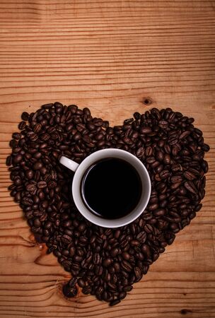 Black coffee on a wooden background surrounded by coffee beansの写真素材