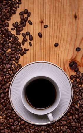 Black coffee on a wooden background surrounded by coffee beansの写真素材