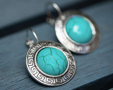 two silver earrings on a blue wooden backgroundの写真素材