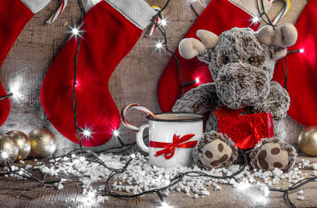 reindeer sitting on a wooden background surrounded with christmas decorationsの写真素材