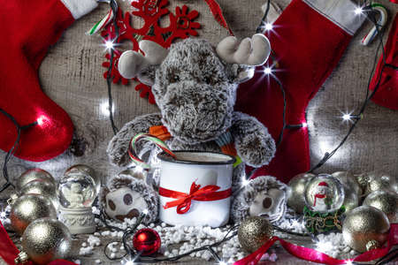 reindeer sitting on a wooden background surrounded with christmas decorationsの写真素材