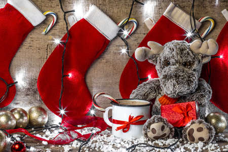 reindeer sitting on a wooden background surrounded with christmas decorationsの写真素材