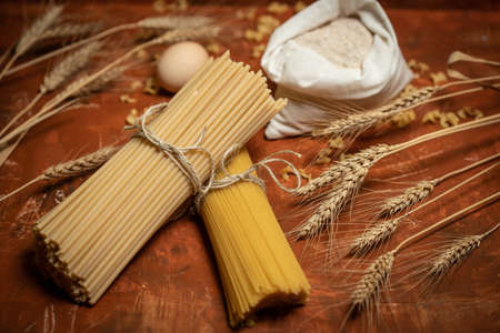 Dry pasta with flour and egg on a brown, rustic bacgkround. Diet and food concept.の写真素材