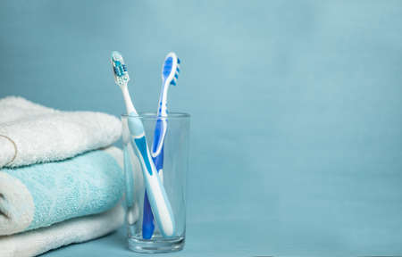 Two blue thootbrush in a glass with towels on a blue background with copy space. Health concept.の写真素材