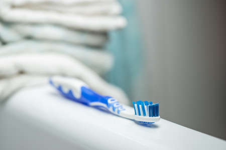 Blue toothbrush in the bathroom surrounded with white towels. Health concept.の写真素材