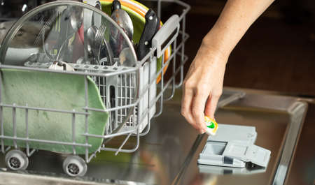 Woman putting the cleaning pillow into the dishwasher.の写真素材