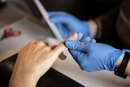 Closeup shot of a woman in a nail salon receiving a manicure by a butician. Woman getting nail manicure.の写真素材