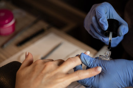 Closeup shot of a woman in a nail salon receiving a manicure by a butician. Woman getting nail...