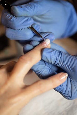 Closeup shot of a woman in a nail salon receiving a manicure by a butician. Woman getting nail...